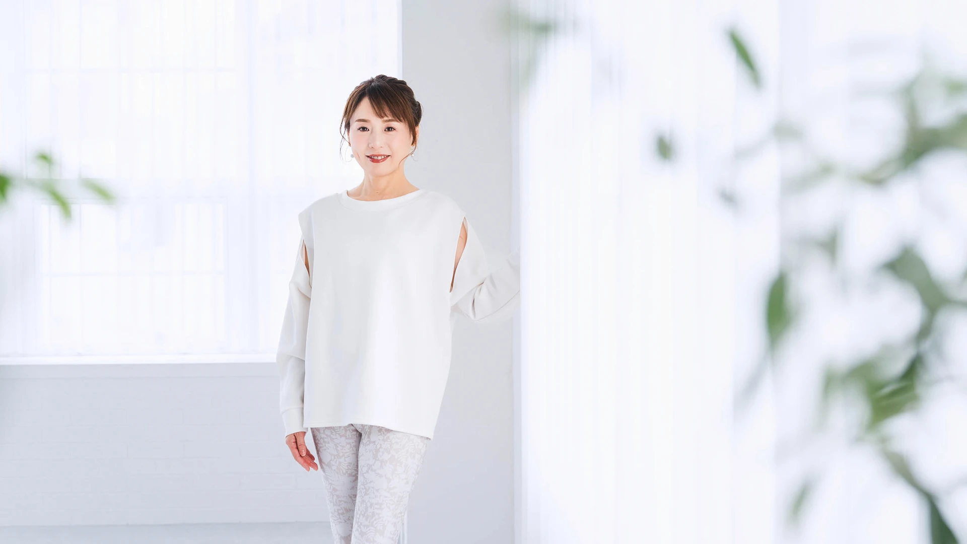 明るい室内で白い服を着て微笑む斎名智子